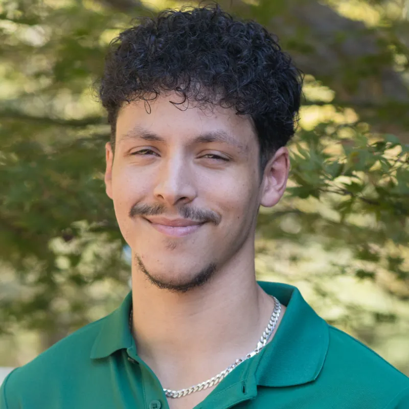 Profile photo of Alexander Beets smiling, wearing a green polo shirt with the UNC Charlotte logo