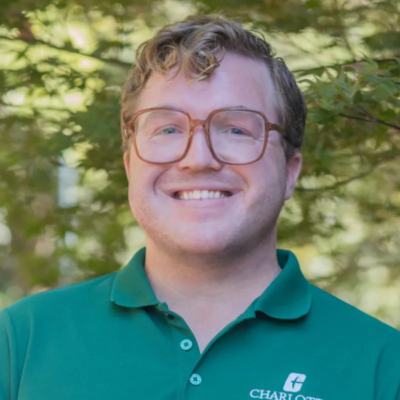 Profile photo of Joshua Wood smiling, wearing a green polo shirt with the UNC Charlotte logo
