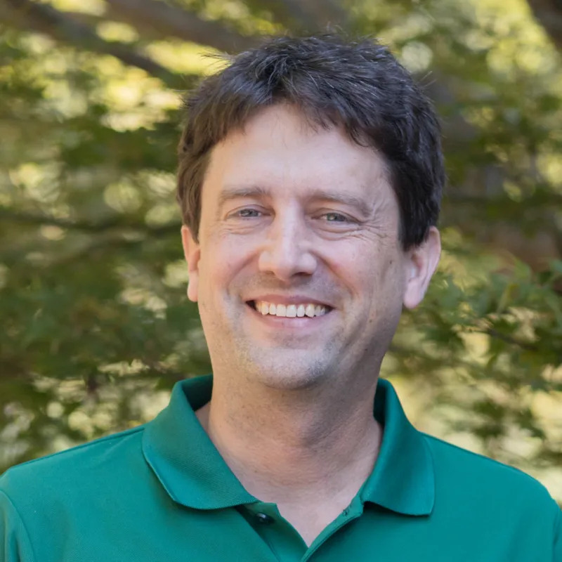Profile photo of Justin Paprocki smiling, wearing a green polo shirt with the UNC Charlotte logo