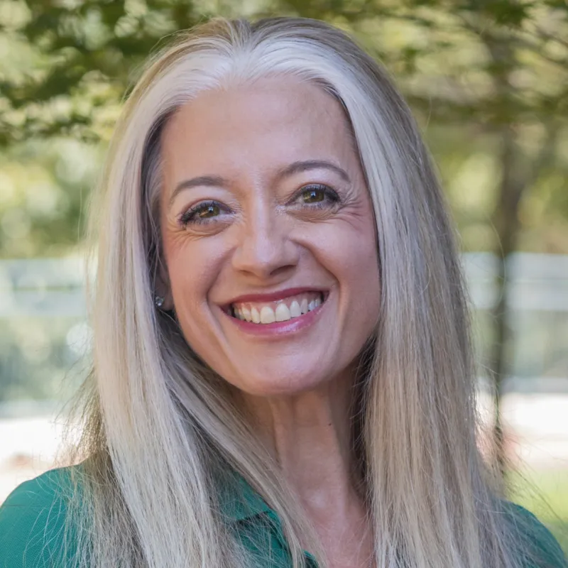 Profile photo of Kelly Merges smiling, wearing a green polo shirt with the UNC Charlotte logo