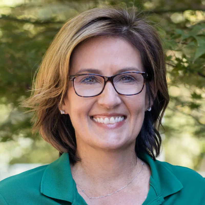 Profile photo of Laurie Cuddy smiling, wearing a green polo shirt with the UNC Charlotte logo