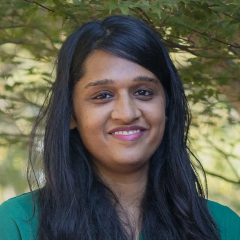 Profile photo of Preeti Ganesh smiling, wearing a green polo shirt with the UNC Charlotte logo